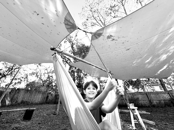 our child, otto, sitting in a hammock under a rainshade