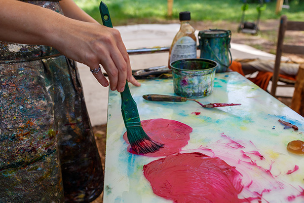 Ruth Whiting using a palette knife to paint kinetic art elements outside