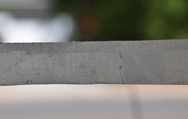 Old ripstop repair tape peeled back showing collected sand and grime